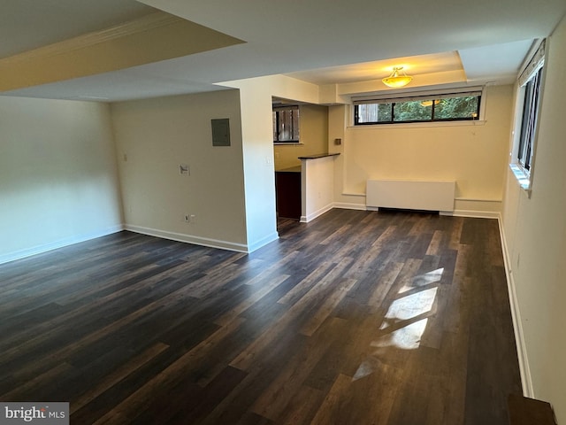 unfurnished living room featuring crown molding, radiator, a raised ceiling, and dark hardwood / wood-style flooring