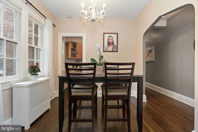 dining area with dark wood-type flooring, an inviting chandelier, and a healthy amount of sunlight