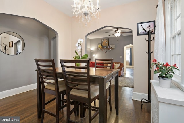 dining space with ceiling fan with notable chandelier and dark hardwood / wood-style flooring