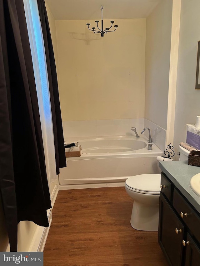 full bath with a garden tub, vanity, toilet, and wood finished floors