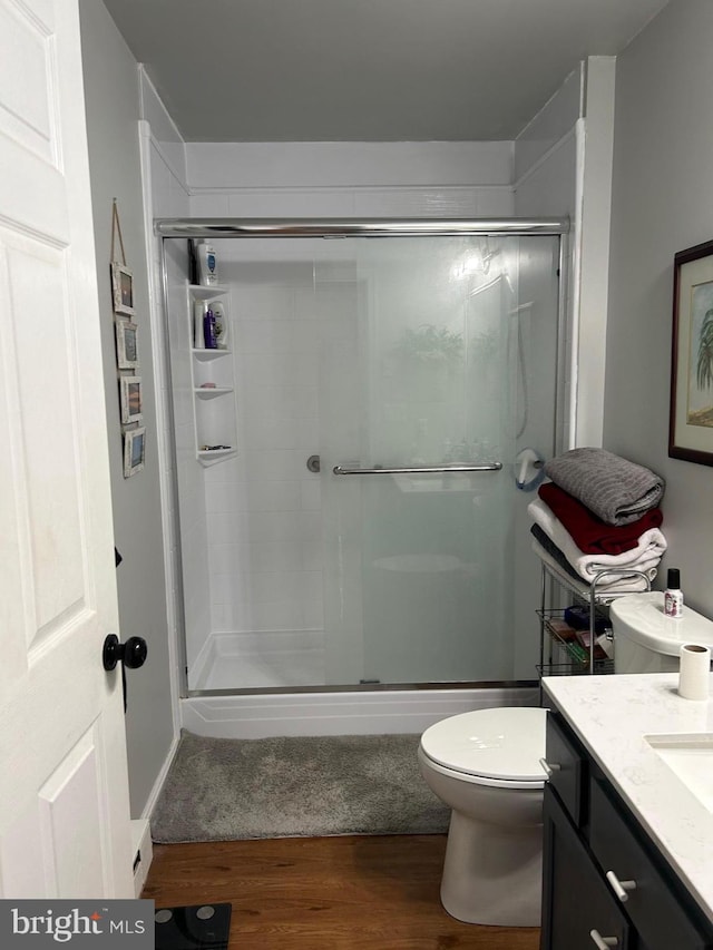 bathroom featuring a stall shower, toilet, and wood finished floors