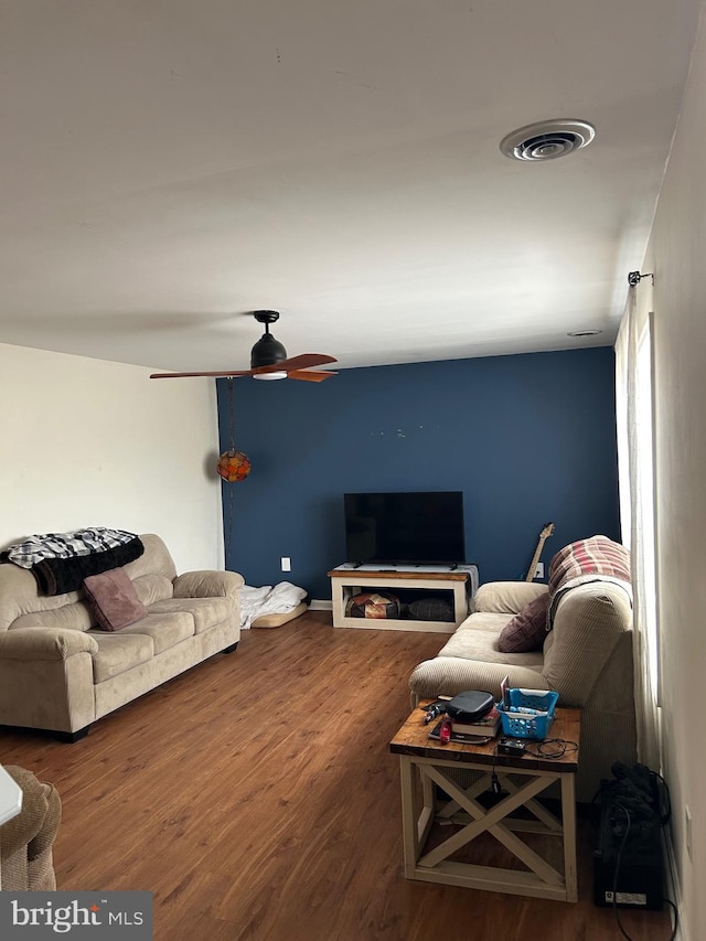 living room featuring visible vents, ceiling fan, and wood finished floors