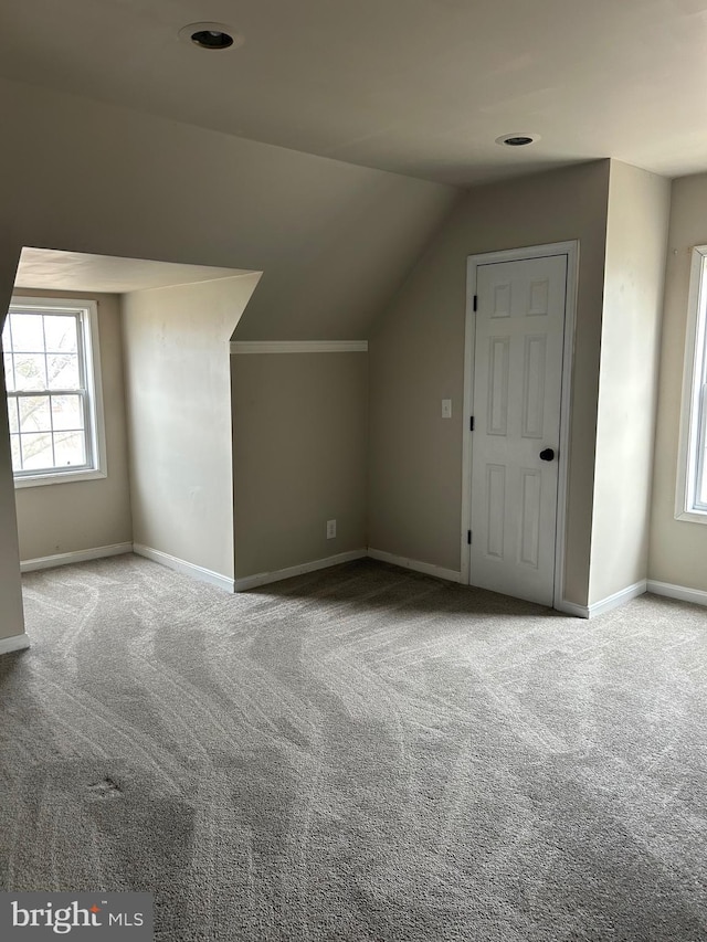 additional living space with baseboards, vaulted ceiling, and carpet flooring