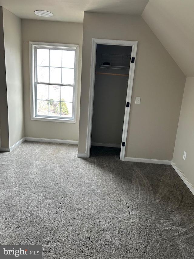 interior space featuring lofted ceiling, carpet, and baseboards