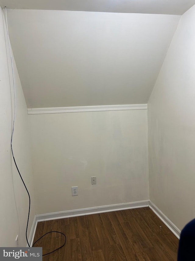 bonus room with baseboards and dark wood-style flooring