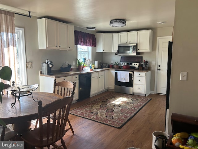 kitchen with white cabinets, stainless steel appliances, a sink, and wood finished floors