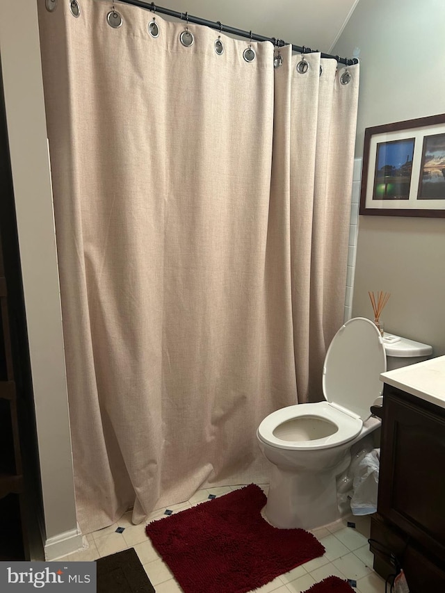 bathroom with a shower with curtain, vanity, toilet, and tile patterned floors