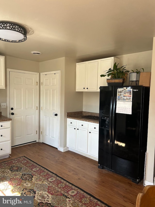 kitchen with dark countertops, dark wood finished floors, white cabinets, and black fridge with ice dispenser