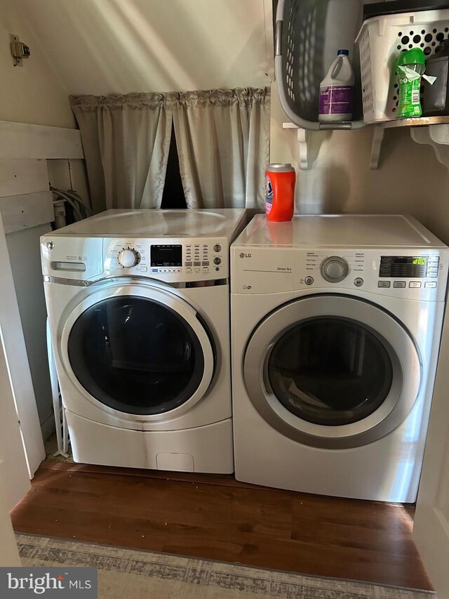 laundry room with laundry area, wood finished floors, and washing machine and clothes dryer