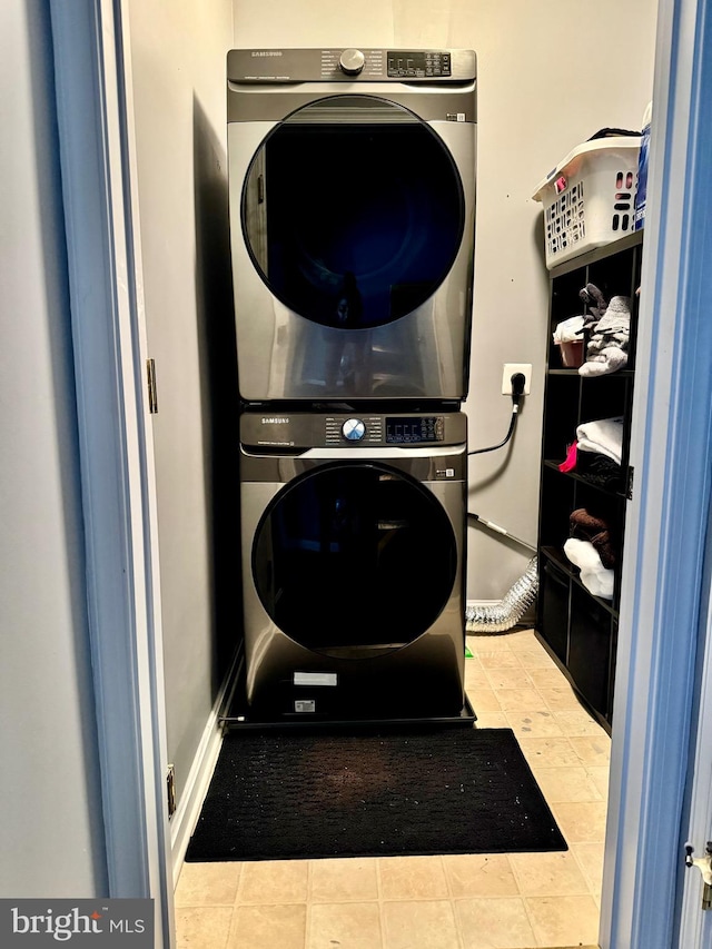 laundry area with light tile patterned floors and stacked washing maching and dryer