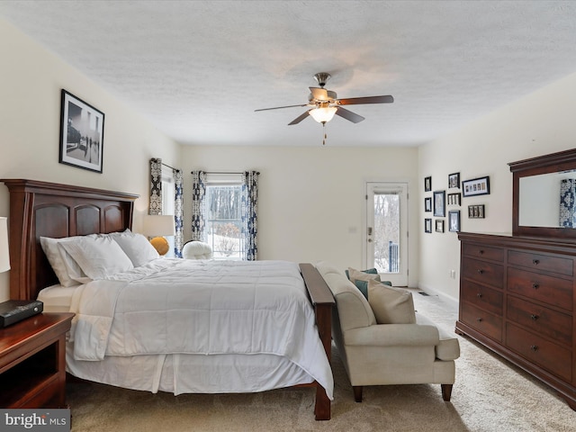 bedroom featuring light colored carpet, a textured ceiling, and ceiling fan