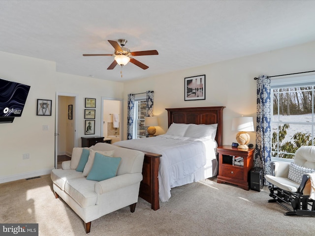 bedroom featuring ceiling fan, ensuite bath, and light carpet