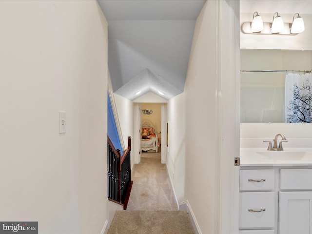 hallway with sink and light colored carpet