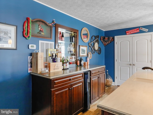 bar with light hardwood / wood-style floors, sink, and a textured ceiling