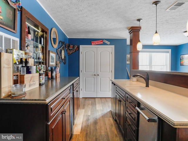 kitchen with sink, wood-type flooring, decorative light fixtures, dark brown cabinets, and a textured ceiling