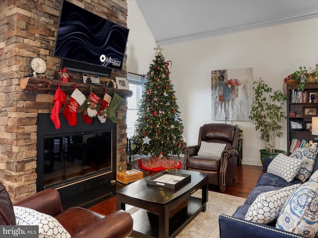 living room featuring hardwood / wood-style floors, crown molding, a fireplace, and vaulted ceiling