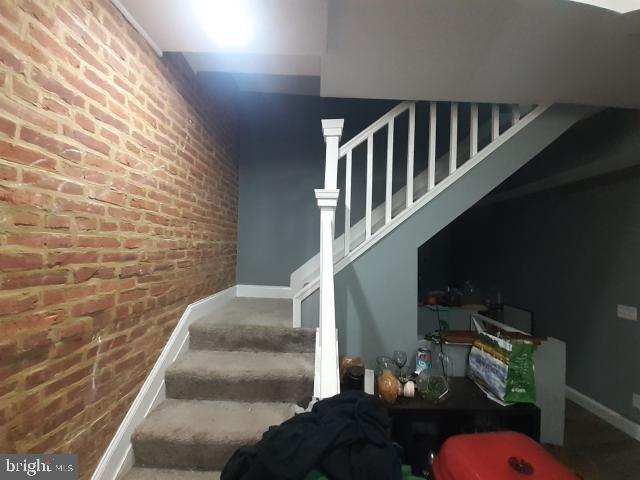 staircase featuring brick wall