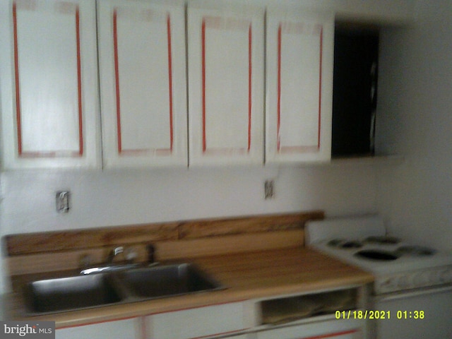 kitchen featuring white stove, sink, and white cabinets