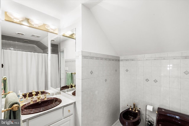 bathroom featuring a bidet, tile walls, vaulted ceiling, and vanity