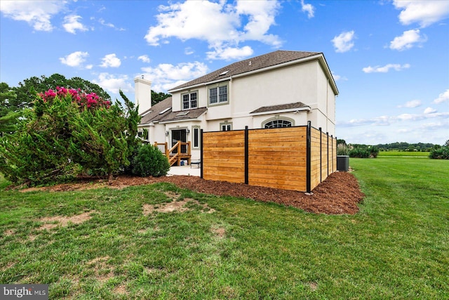 rear view of house featuring cooling unit, a lawn, and a patio area