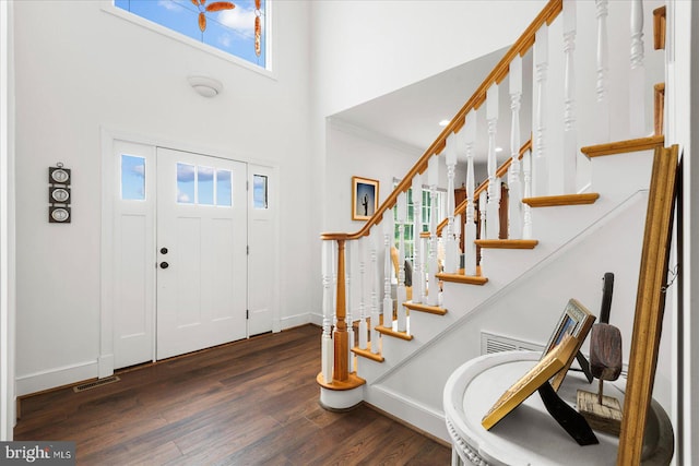 foyer with a high ceiling, plenty of natural light, dark hardwood / wood-style floors, and ornamental molding