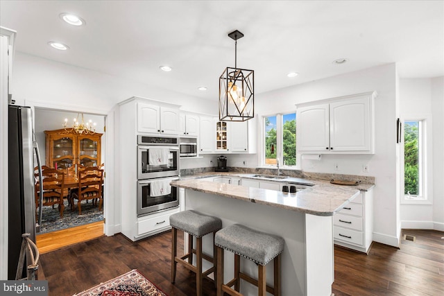 kitchen featuring dark wood-type flooring, a kitchen island, stainless steel appliances, and a notable chandelier