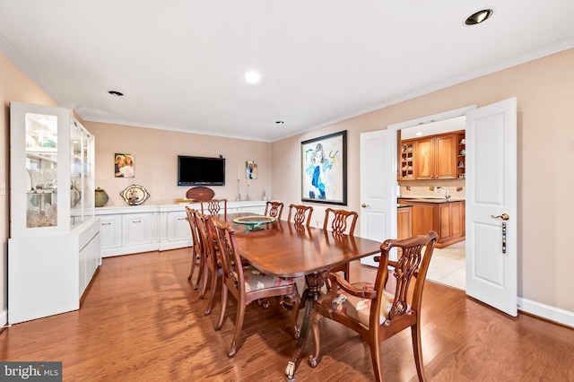 dining room with light wood-style floors, ornamental molding, and recessed lighting