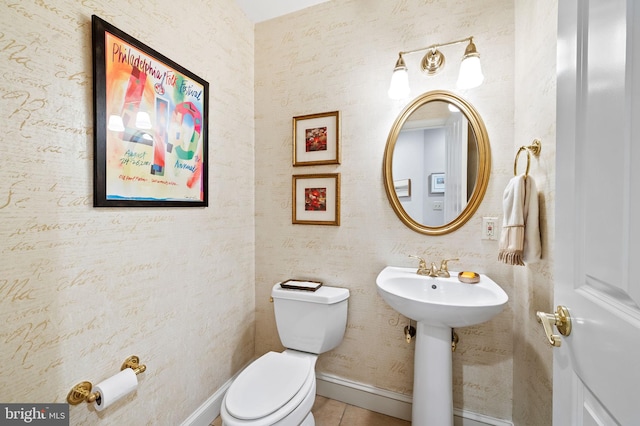 half bathroom featuring baseboards, tile patterned flooring, toilet, and wallpapered walls