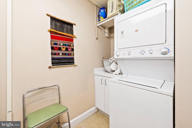 washroom with cabinet space, stacked washing maching and dryer, baseboards, and light tile patterned flooring