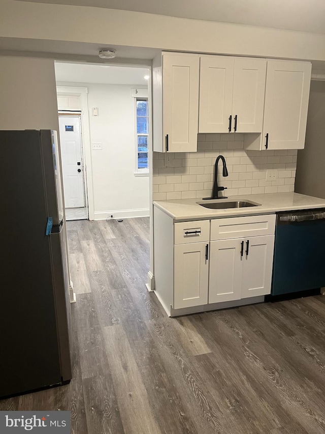 kitchen with black dishwasher, sink, stainless steel fridge, and white cabinetry