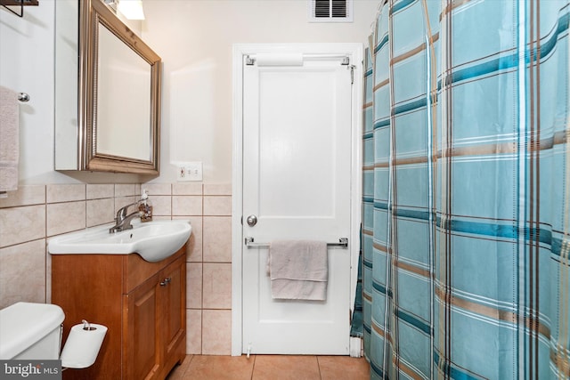 bathroom featuring toilet, tile patterned flooring, vanity, tile walls, and a shower with shower curtain