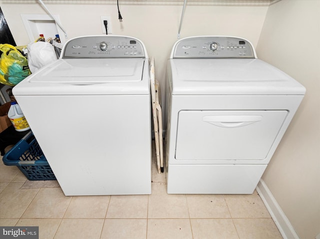 clothes washing area with separate washer and dryer and light tile patterned floors