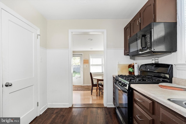 kitchen with black appliances, dark hardwood / wood-style floors, and dark brown cabinets