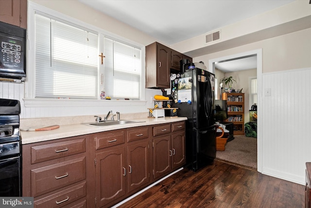 kitchen featuring black appliances, dark hardwood / wood-style flooring, dark brown cabinetry, and sink