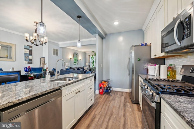 kitchen featuring white cabinetry, appliances with stainless steel finishes, hanging light fixtures, and sink