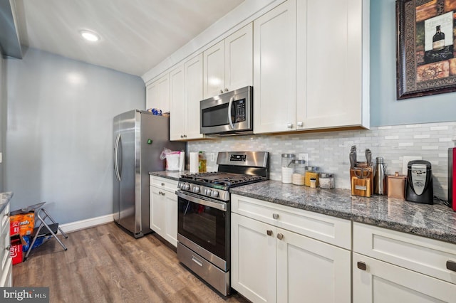 kitchen featuring white cabinetry, backsplash, dark hardwood / wood-style flooring, stainless steel appliances, and dark stone counters