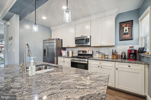 kitchen featuring appliances with stainless steel finishes, dark stone countertops, pendant lighting, and white cabinets