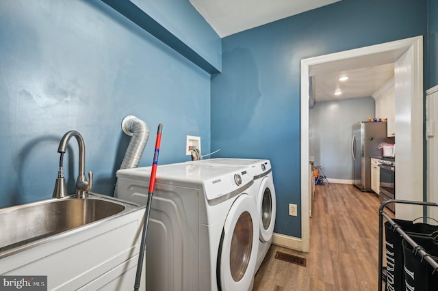 washroom featuring washing machine and clothes dryer, hardwood / wood-style flooring, and sink