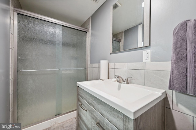 bathroom with tile walls, a shower with door, and vanity