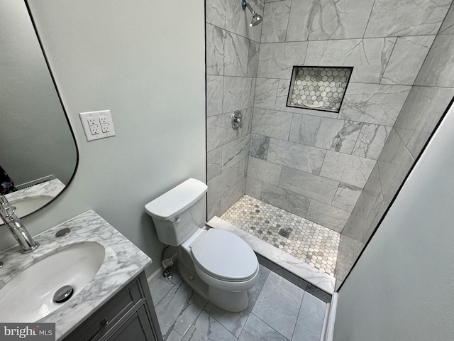 bathroom featuring vanity, toilet, and a tile shower