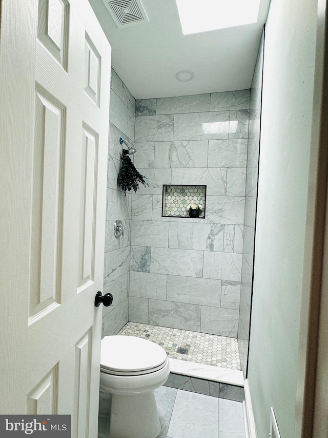 bathroom featuring toilet and a tile shower