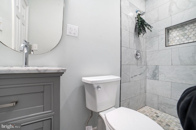 bathroom with vanity, a tile shower, and toilet