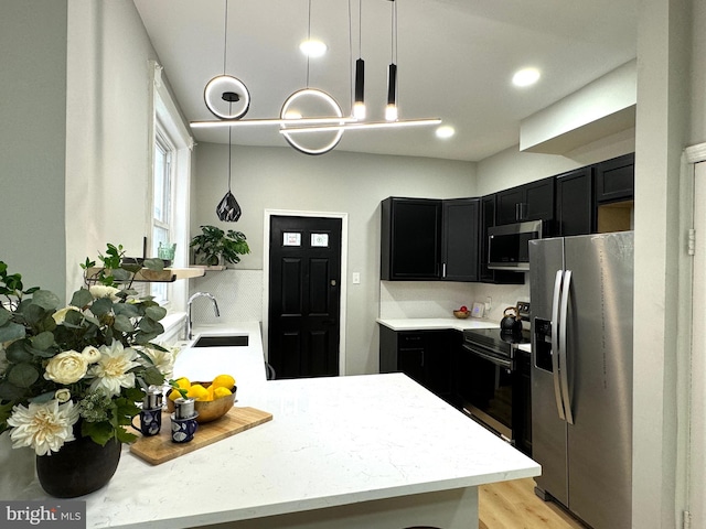 kitchen featuring pendant lighting, sink, light wood-type flooring, kitchen peninsula, and stainless steel appliances