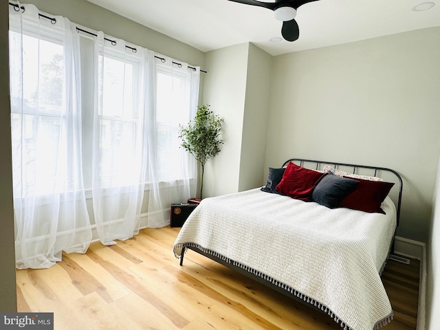 bedroom featuring hardwood / wood-style floors, ceiling fan, and multiple windows