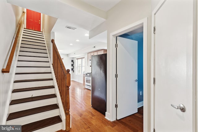 stairway featuring recessed lighting, visible vents, baseboards, and wood finished floors