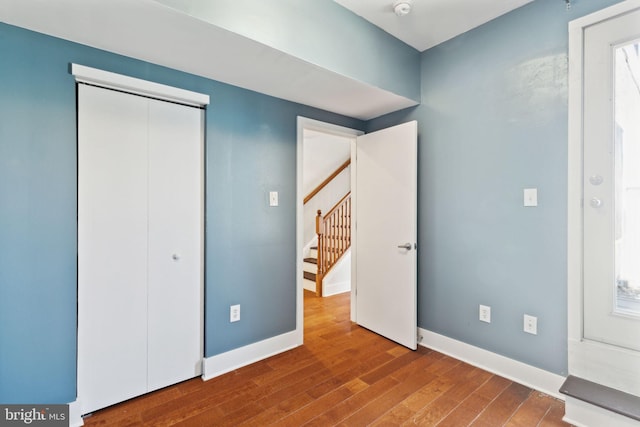 unfurnished bedroom featuring wood finished floors, baseboards, and a closet