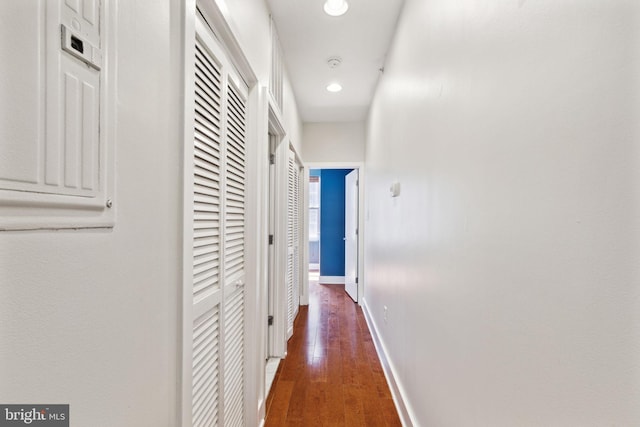 corridor with recessed lighting, wood finished floors, baseboards, and a heating unit