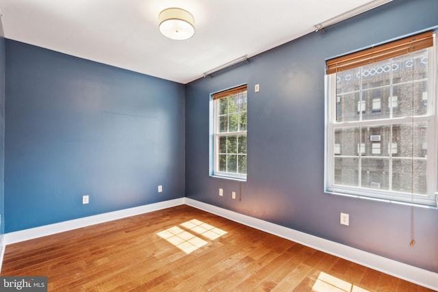 unfurnished room featuring baseboards and wood-type flooring