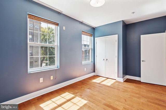 unfurnished bedroom featuring a closet, baseboards, and wood finished floors