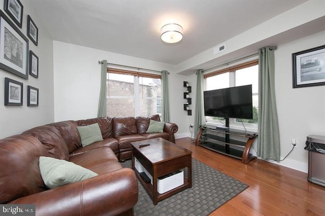 living room with wood finished floors, visible vents, and baseboards